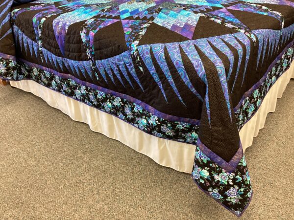 The Amazon Star border-The border is a black background fabric printed with a purple and blue floral pattern representing all the colors in the quilt.