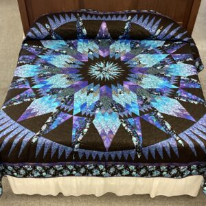 A dramatic presentation of shades of purple and blues with black, entitled A Spinning Trip. An Amazon Star pattern quilt created by a local Amish artisan.