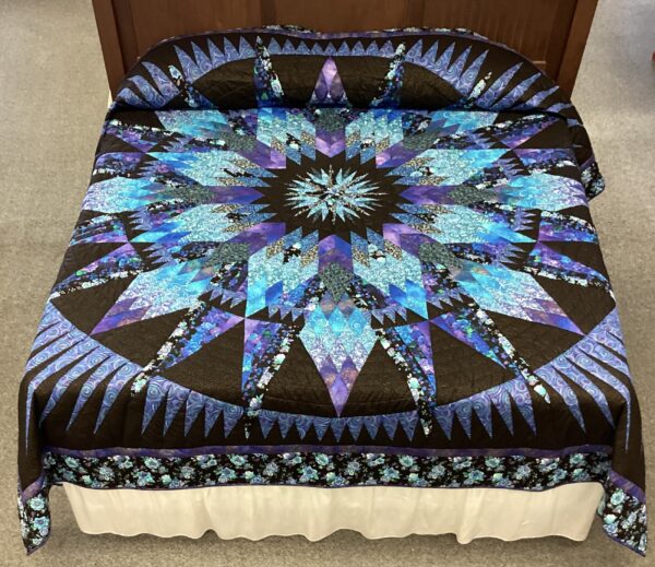 A dramatic presentation of shades of purple and blues with black, entitled A Spinning Trip. An Amazon Star pattern quilt created by a local Amish artisan.